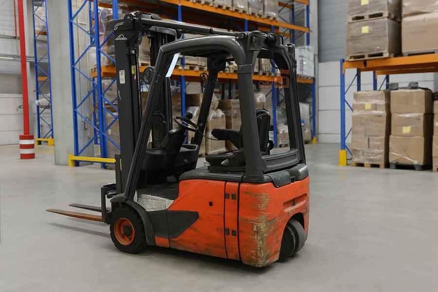 Трёхопорный электропогрузчик, аналогичный Linde, установленный на складе; вид сбоку с двумя передними колёсами и одним центральным задним колесом.