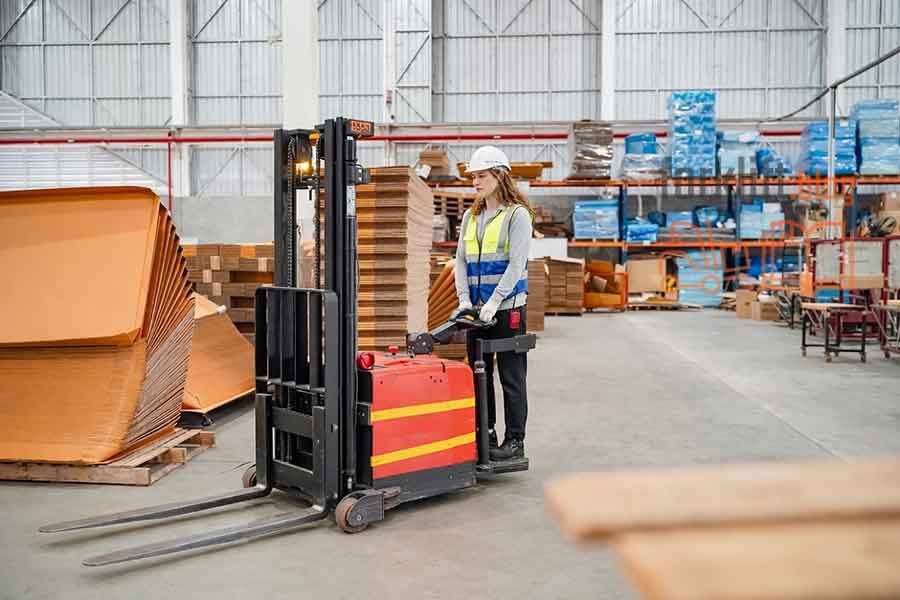 Женщина-оператор управляет электрическим штабелером на складе — надёжность, безопасность и равные возможности в современной логистике.
