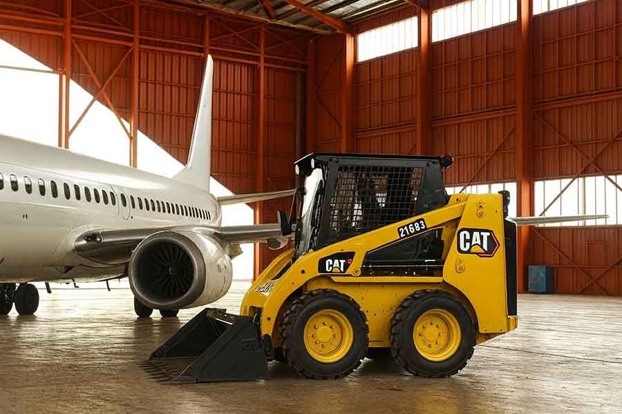 Мини-погрузчик Caterpillar 216B3 работает внутри ангара аэропорта