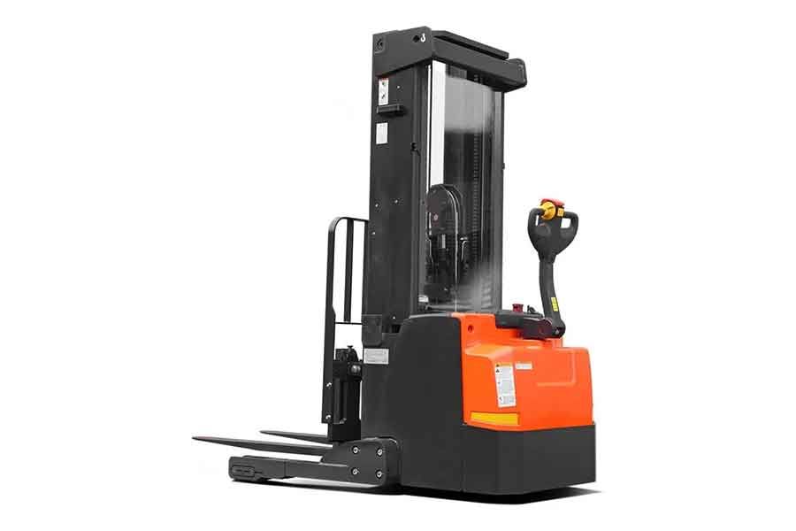 Электрический штабелёр оранжевого и чёрного цвета, стоящий на производственной площадке среди оборудования и паллет